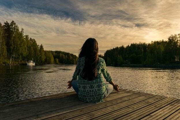 Ženska meditira ob jezeru.