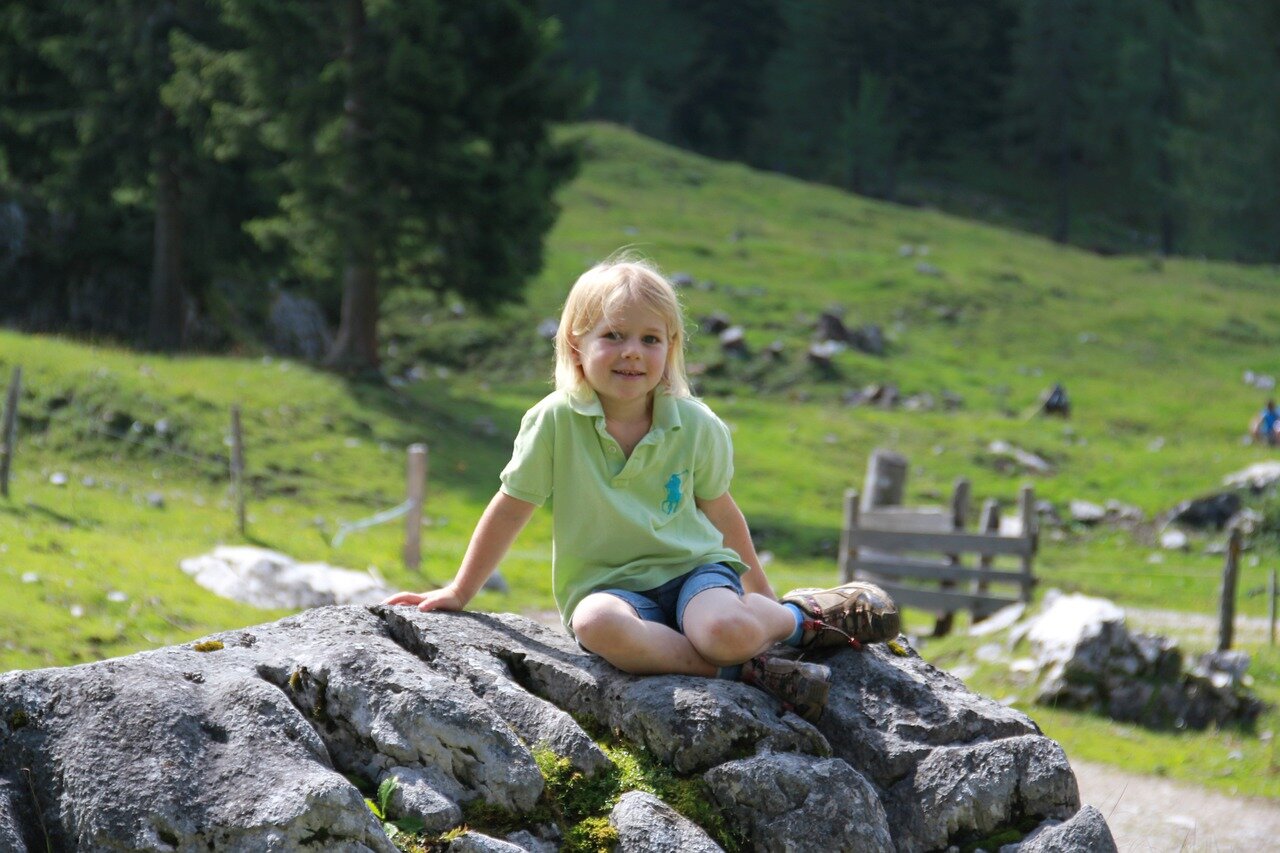 Deklica v pohodnih čevljih sedi na skali.